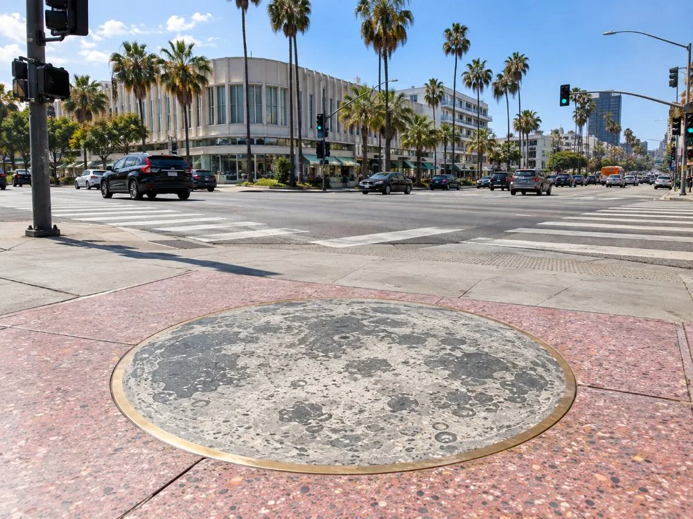 The corner of Hollywood and Vine with a round moon monument in the sidewalk